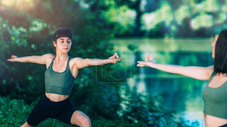 Foto de Mujeres de Yoga junto al Lago. Pose guerrero - Imagen libre de derechos