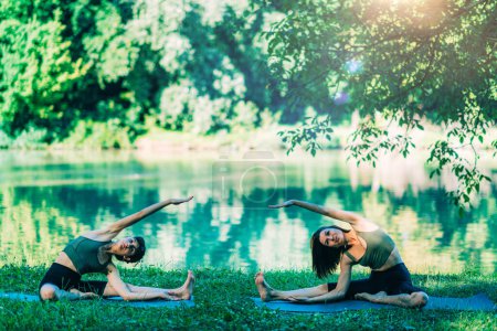 Téléchargez les photos : Mindfulness and Meditation. Women Doing Yoga by the Lake - en image libre de droit