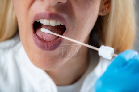 Photo for Woman Inserting a swab into the mouth, collecting a saliva sample for DNA analysis - Royalty Free Image