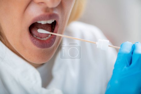 Téléchargez les photos : Femme Insertion d'un écouvillon dans la bouche, prélèvement d'un échantillon de salive pour analyse ADN - en image libre de droit