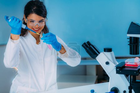 Photo for Student in White Coat, Working in Research Laboratory Using Micro Pipette and Test Tube - Royalty Free Image