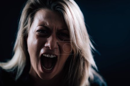 Téléchargez les photos : Anger - intense portrait of an angry woman on black background - en image libre de droit