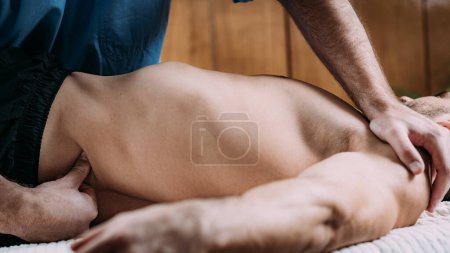 Foto de Sports injury physical therapy treatment. Physical therapist massaging male patient with injured back. - Imagen libre de derechos