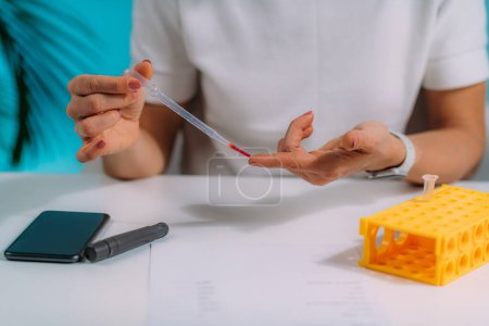 Téléchargez les photos : Femme Mesurer les niveaux de glucose dans le sang, en utilisant un téléphone intelligent pour suivre le résultat - en image libre de droit