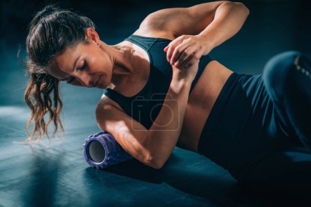 Photo for Female Athlete Massaging Shoulders with Foam Roller - Royalty Free Image