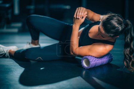 Photo for Foam Roller. Sportswoman Using Foam Roller Massager to Stretch Muscles - Royalty Free Image