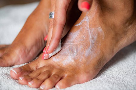 Téléchargez les photos : Femme appliquant crème pour les pieds - en image libre de droit