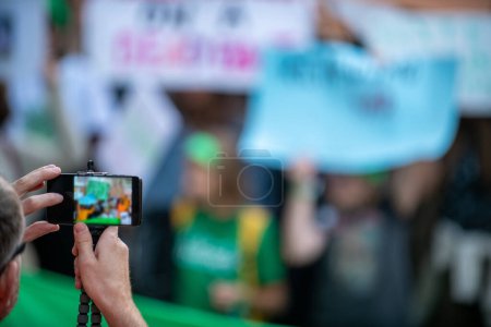 Téléchargez les photos : Climate Change Protest on the Street. Focus on Man Holding Phone and Recording Protest. - en image libre de droit