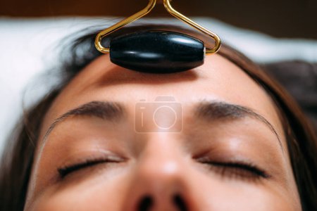 Téléchargez les photos : Guasha Face Massage with Jade Stone Roller - en image libre de droit