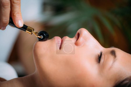 Téléchargez les photos : Massage de drainage lymphatique du visage Guasha avec rouleau en pierre de jade - en image libre de droit