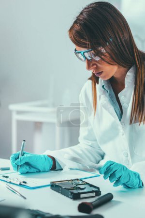Foto de Ciencias forenses en el laboratorio. Científico forense examinando el disco duro con evidencias - Imagen libre de derechos