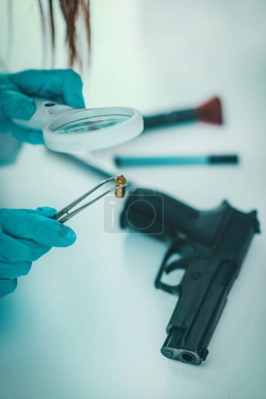 Téléchargez les photos : La criminalistique au labo. Scientifique légiste examinant une balle avec des preuves - en image libre de droit