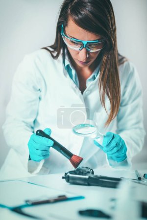 Foto de Ciencias forenses en el laboratorio. Científico forense examinando arma con evidencias - Imagen libre de derechos