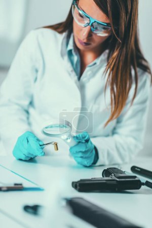 Foto de Ciencias forenses en el laboratorio. Científico forense examinando proyectil con evidencias - Imagen libre de derechos