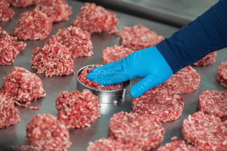 Téléchargez les photos : Faire des galettes de hamburger en utilisant un moule à anneau dans une cuisine commerciale - en image libre de droit