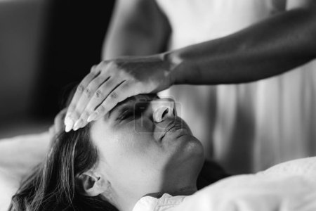 Reiki Healing. Frau liegt mit geschlossenen Augen in Behandlung. 