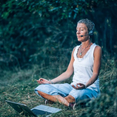 Foto de Meditación en línea. Entrenadora de desarrollo personal meditando con sus clientes a través de Internet - Imagen libre de derechos