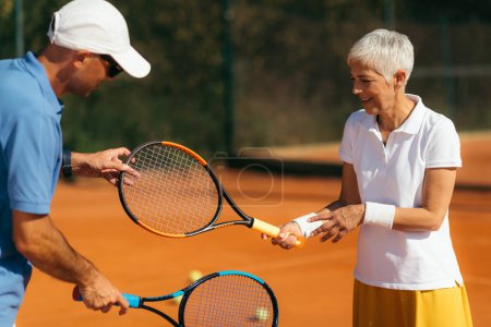 Foto de Entrenamiento de tenis para personas mayores con instructor - Imagen libre de derechos