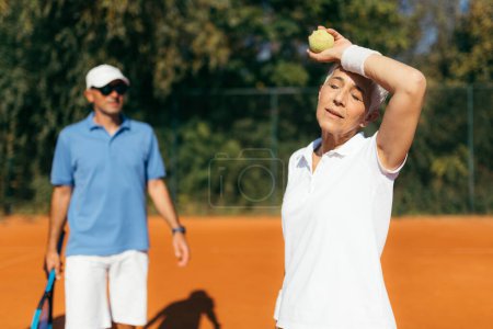 Foto de Madura mujer jugando al tenis con instructor - Imagen libre de derechos