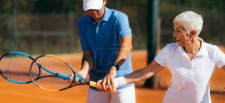Foto de Instructor de tenis con mujer mayor, clase de tenis - Imagen libre de derechos