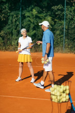 Foto de Entrenamiento de tenis para personas mayores con instructor - Imagen libre de derechos