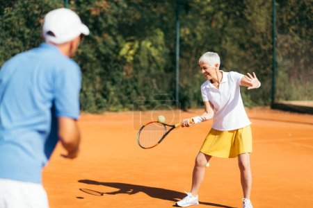 Photo for Mature Woman Playing Tennis with instructor - Royalty Free Image