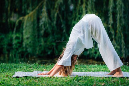Téléchargez les photos : Du yoga. Femme faisant du yoga au bord du lac, fond vert. - en image libre de droit