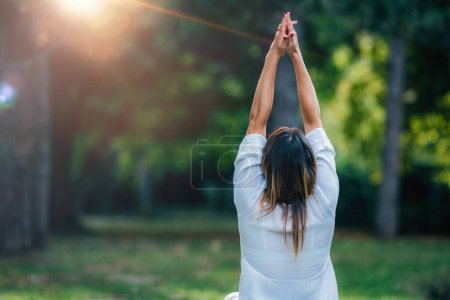 Téléchargez les photos : Meditation. Young woman practicing yoga and meditating by the water. - en image libre de droit