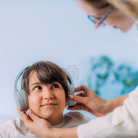 Photo for Pure tone audiometry test, checking childs ability to hear different pitches and volumes of sound. Boy Child with headphones listening sounds with different pitches and volumes, responding. - Royalty Free Image
