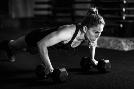 Foto de Entrenamiento cruzado. Mujer joven haciendo ejercicio con pesas - Imagen libre de derechos