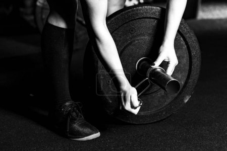 Photo for Cross training. Female athlete changing weights on barbells - Royalty Free Image