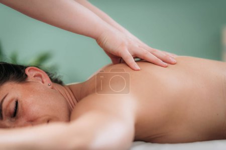 Téléchargez les photos : Massage relaxant pour les épaules et le cou, les mains d'un massothérapeute massant les épaules d'une cliente - en image libre de droit