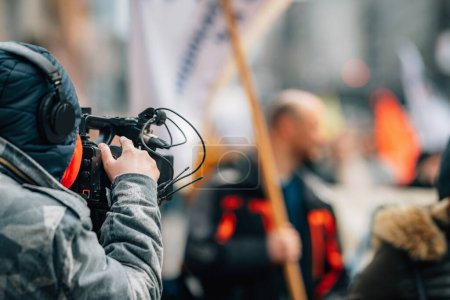 Photo for News crew reporting from the city streets during public protests, crowd in the background - Royalty Free Image
