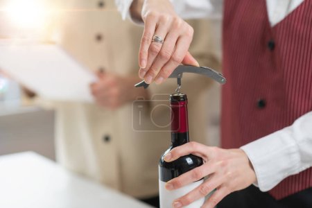 Téléchargez les photos : Cours d'éducation au vin. Un sommelier démontre comment insérer un tire-bouchon dans le bouchon, ce qui est une compétence fondamentale pour ouvrir une bouteille de vin. - en image libre de droit
