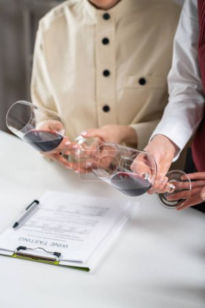 Téléchargez les photos : Dégustation de vin rouge. Les participants comparent les couleurs des différents vins rouges lors d'une dégustation de vin, apprenant à identifier l'âge du vin, le cépage et d'autres détails clés basés sur la teinte. - en image libre de droit