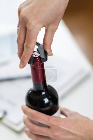 Téléchargez les photos : Expérience de dégustation de vin. Le sommelier enlève la feuille recouvrant le dessus d'une bouteille de vin, tout en expliquant la bonne façon de préparer une bouteille de vin pour le service. - en image libre de droit