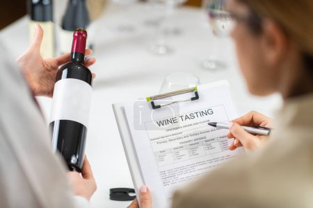 Photo for Wine tasting workshop. Participants fill out a wine tasting form, taking note of the wine's appearance, aroma, taste, and finish to develop their wine-tasting skills. - Royalty Free Image