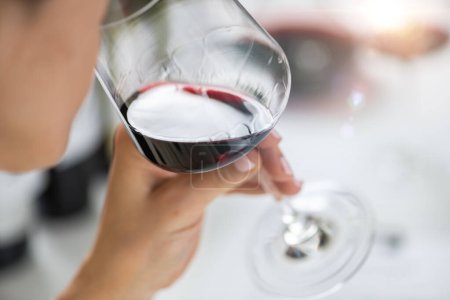 Foto de Degustación de vinos. Una mujer disfruta de una degustación de vino tinto, saboreando los sabores y aromas del vino. - Imagen libre de derechos
