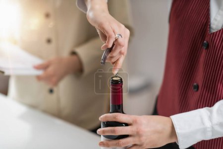 Photo for Wine education course. A sommelier demonstrates how to insert a corkscrew into the cork, which is a fundamental skill for opening a bottle of wine. - Royalty Free Image
