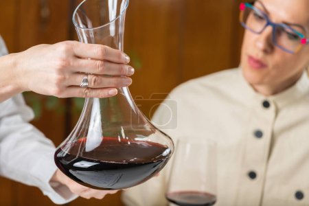 Photo for Wine tasting event, quality assessment. A sommelier looks at the wine in a decanter and explains how to evaluate its quality based on appearance, aroma, taste, and finish. - Royalty Free Image