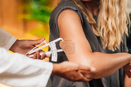 Téléchargez les photos : Diététiste mesure la graisse corporelle, à l'aide d'étrier sur le bras de la patiente - en image libre de droit