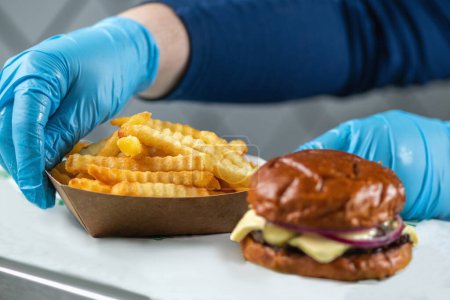Téléchargez les photos : Servant un sandwich burger street food avec des frites - en image libre de droit