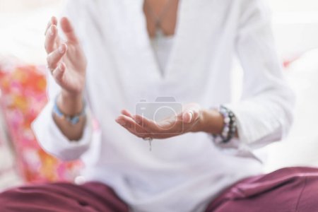Foto de Mujer consciente sentada en posición de loto, meditando, realizando un gesto de respeto con las manos. Despertar espiritualmente. - Imagen libre de derechos
