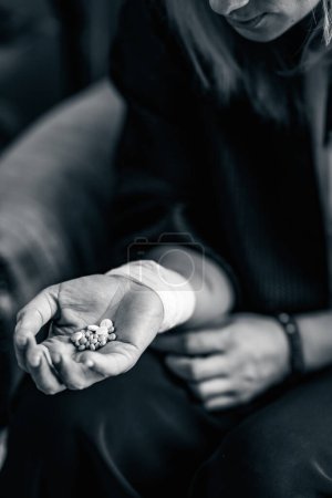 Téléchargez les photos : La main d'une personne prend un tas de pilules antidépresseurs, soulignant le risque d'abus de drogues et le danger de l'automédication sans consultation médicale appropriée. Importance de la sensibilisation à la santé mentale et de l'utilisation appropriée des médicaments d'ordonnance. - en image libre de droit