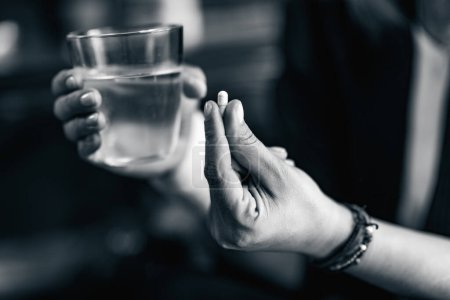 Photo for Psychology. Mental health patient taking pills and holding a glass of water - Royalty Free Image