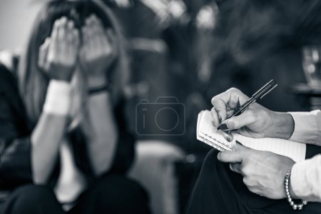 Photo for Psychotherapist taking notes during cognitive behavioral therapy session with patient - Royalty Free Image