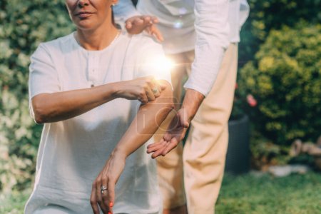 Photo for Reiki Class. Reiki instructor therapist holding hands over the elbow of a patient - Royalty Free Image