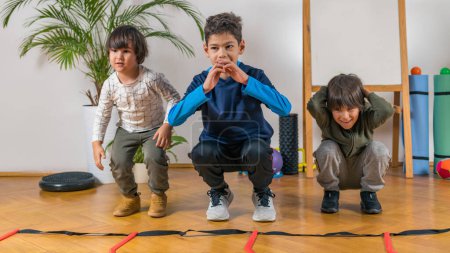 Photo for Three Children Exercising Indoors - Royalty Free Image
