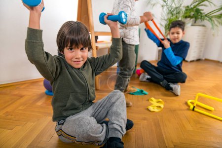 Photo for Children Exercising with Resistance Bands and  Dumbbells Indoors - Royalty Free Image