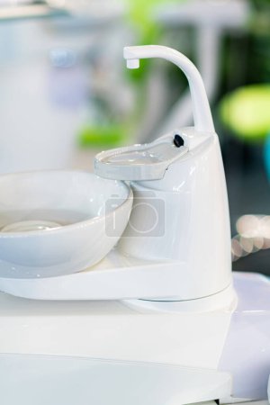 Foto de Silla de dentista, fregadero y consola con equipo en una clínica dental moderna - Imagen libre de derechos